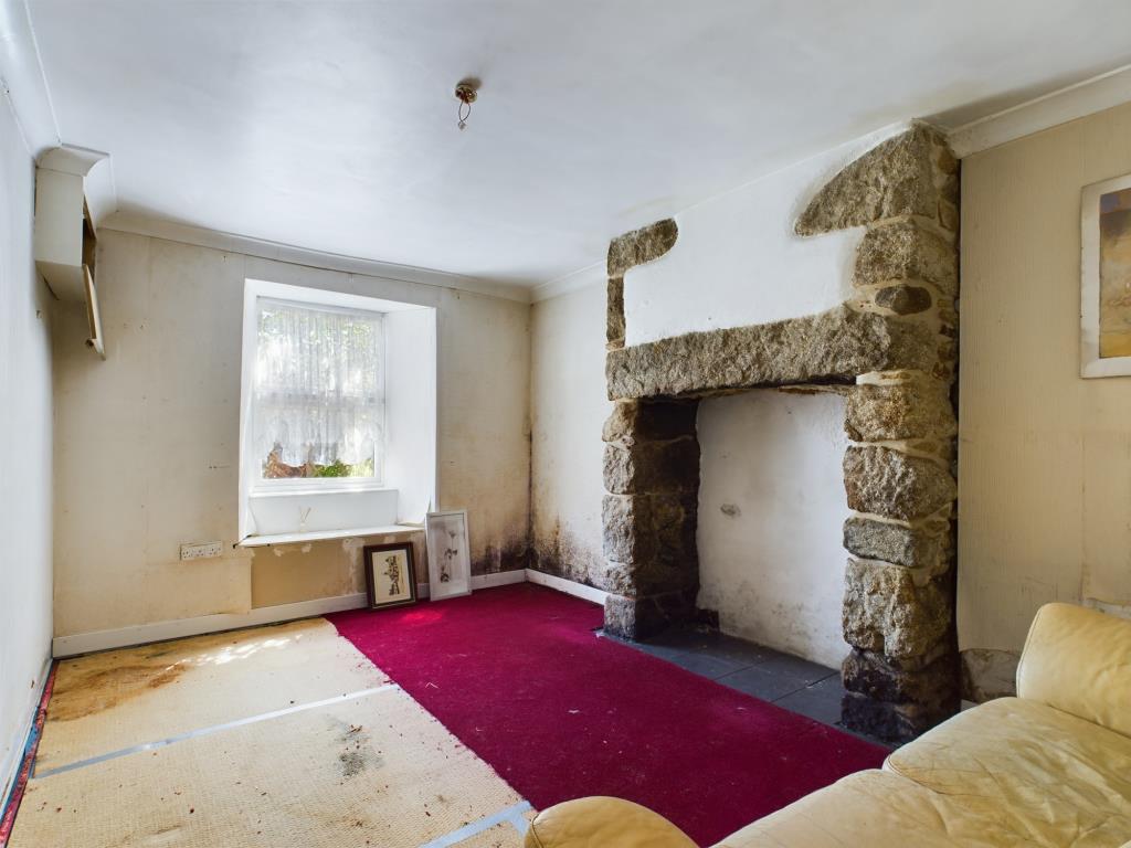 Lot: 62 - END-TERRACE COTTAGE FOR IMPROVEMENT IN VILLAGE LOCATION - Living room with inglenook fireplace